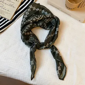 Close-up detail of a retro dark green paisley print silk scarf tied in a fashionable knot