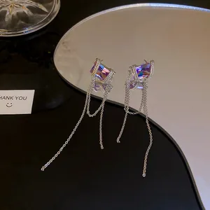 Detailed macro shot of purple gemstone tassel earrings on a minimalist reflective surface