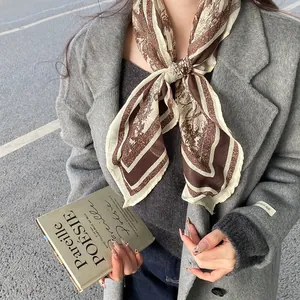Close-up of a retro paisley print silk scarf styled with a grey winter coat