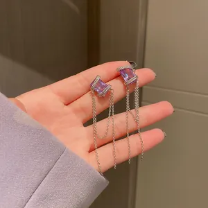 Detailed macro view of purple rectangle gemstone earrings with long silver tassel chains
