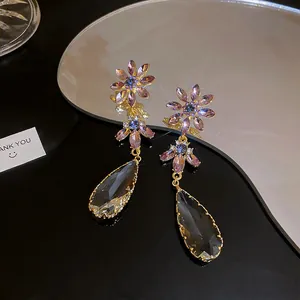Macro view of elegant purple floral crystal earrings featuring gray teardrop pendants.