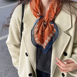 Close-up of vintage orange paisley printed silk scarf tied as a decorative neckpiece
