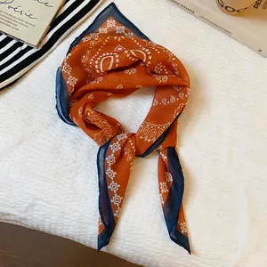 Close-up detail of a vintage orange and navy paisley silk scarf necklace accessory