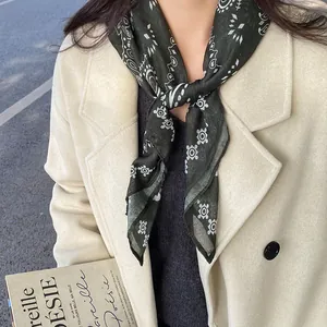 Close-up of a vintage dark green paisley print scarf tied as a stylish necklace detail