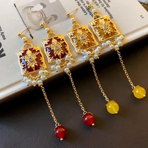 Detailed macro view of elegant vintage style gold earrings with enamel flowers and pearls