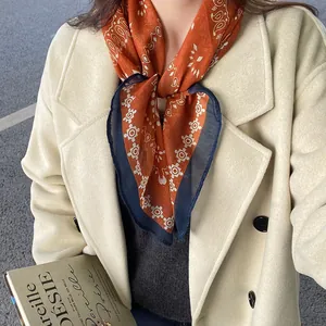 Close-up of vintage paisley print scarf tied on a model with a beige coat.