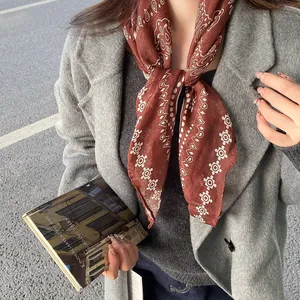 Close-up detail of a vintage paisley printed scarf worn as a neck accessory