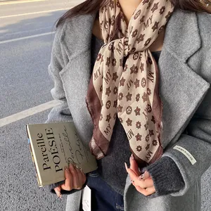 Detail view of a vintage monogram print scarf paired with a stylish gray wool coat