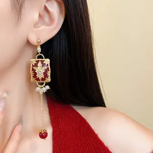 Close-up detail of vintage long dangle earrings with red enamel, pearls and crystals.