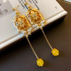Detailed close-up of vintage style floral gold earrings with pearls and long chain drops