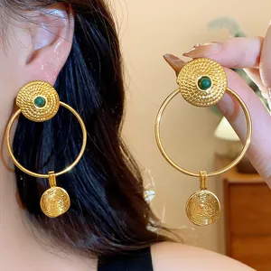 Detailed view of vintage gold plated hoop earrings with textured finish and green stones