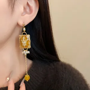 Detail view of a vintage gold-tone earring with amber resin and pearls on a model.