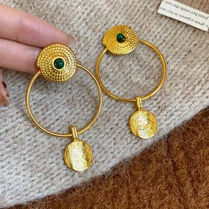 Macro view of vintage gold plated hoop earrings with textured finish and green stone