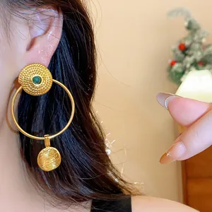 Detail shot of vintage gold-plated hoop earrings with textured finish and green center stone