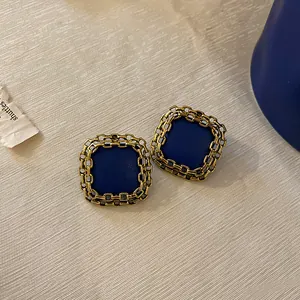 Macro view of vintage Klein blue square earrings featuring intricate gold chain-link borders