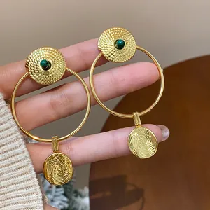 Detailed view of gold-plated hollow hoop earrings featuring textured patterns and green stones