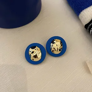 Macro view of Klein blue circular stud earrings with hammered gold irregular metal center