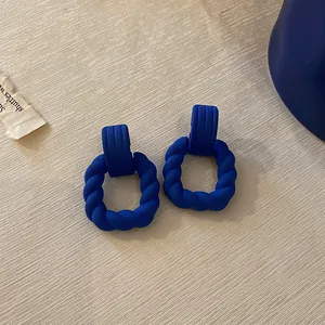 Close-up of matte Klein blue vintage earrings with a twisted square design