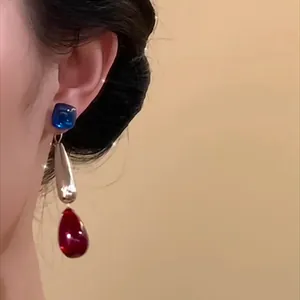 Close-up of retro ethnic acrylic drop tassel earrings with blue and red accents