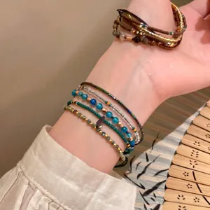 Hand wearing stacked multi-layer ethnic style beaded bracelets with colorful agate beads
