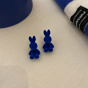 Close-up of cute Klein blue flocked bunny stud earrings with soft velvet texture