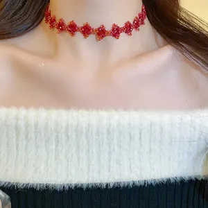 Close-up detail of a handmade red beaded flower choker necklace worn on neck