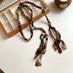 Detailed view of woven fabric waist chain with checkered prints and decorative wooden beads.