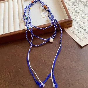 Macro detail of blue and white braided fabric waist chain accessory with decorative beads.