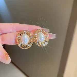Macro view of vintage gold earring featuring central white pearl and rhinestone swirl details