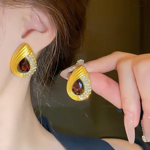 Détail macro de boucles d'oreilles vintage en forme de goutte d'eau dorées avec pierre rouge
