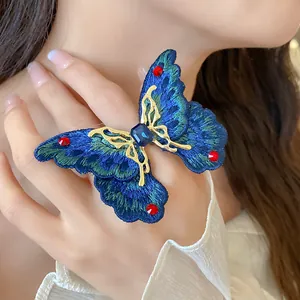 Dettaglio di uno squisito anello a farfalla ricamato blu con strass scintillanti.