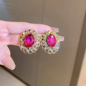 Close-up detail of vintage style earrings with pink oval gemstone and gold filigree.