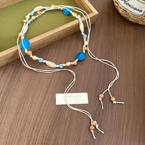 Close-up detail of bohemian waist chain with blue and yellow beads on white cord belt.