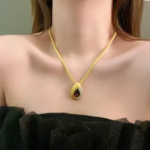 Vue détaillée d'un collier vintage doré avec un pendentif goutte d'eau et cristaux.