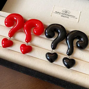 Detailed macro view of red and black question mark earrings with heart charms