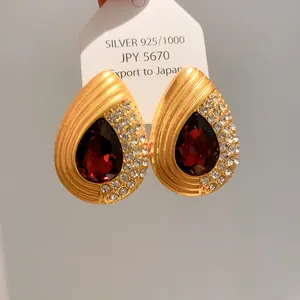 Gros plan de boucles d'oreilles vintage dorées en forme de goutte avec pierre rouge