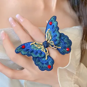 Dettaglio di un pregiato anello a farfalla ricamato blu con una gemma blu scintillante