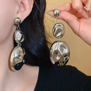 Macro view of oversized silver pleated oval earrings with a liquid molten metal texture