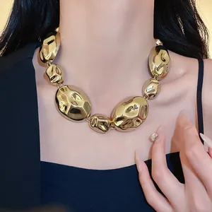 Close-up of chunky gold pleated oval necklace showing unique crumpled texture and fit.