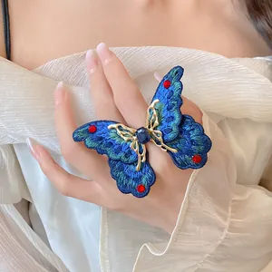 Primo piano dettagliato di un anello a farfalla ricamato blu con strass rossi brillanti