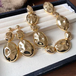 Detail of hammered gold oval necklace and matching earrings in display tray