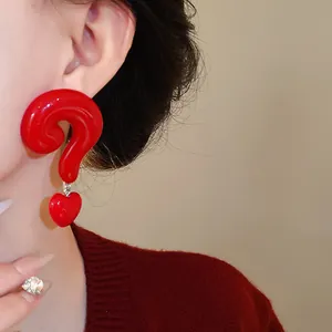 Close-up shot of a unique red question mark earring with heart drop on an Asian model's ear