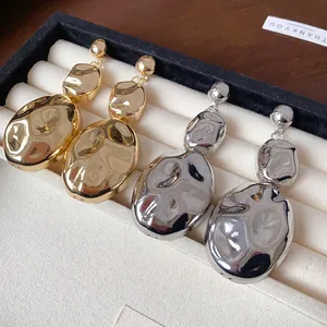 Close-up of gold and silver wrinkled oval earrings in a luxury jewelry display box.
