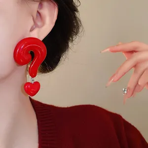 Exaggerated red question mark and heart shaped drop earrings shown on an Asian model