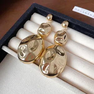 Detail shot of gold-plated wrinkled irregular oval drop earrings in jewelry box