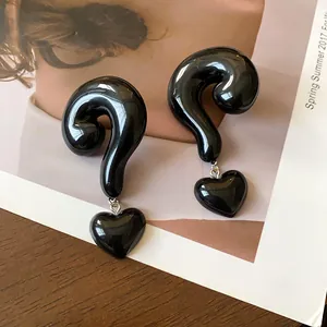 Detailed macro view of glossy black question mark earrings with heart dangles.