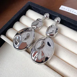 Detailed macro view of silver metallic wrinkled oval drop earrings inside a premium jewelry box
