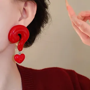 Detailed close-up showing unique red question mark and heart drop earrings on a model.