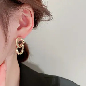Close-up detail of real gold-plated geometric chain earrings worn by a model