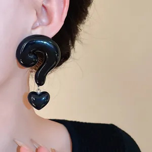 Detailed close-up view of creative black heart symbol earrings worn on the model's ear